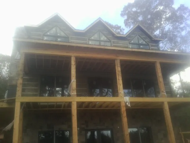 Dormers and porch framing on a large log home under construction — Roof Coating work by our crew in Garvin