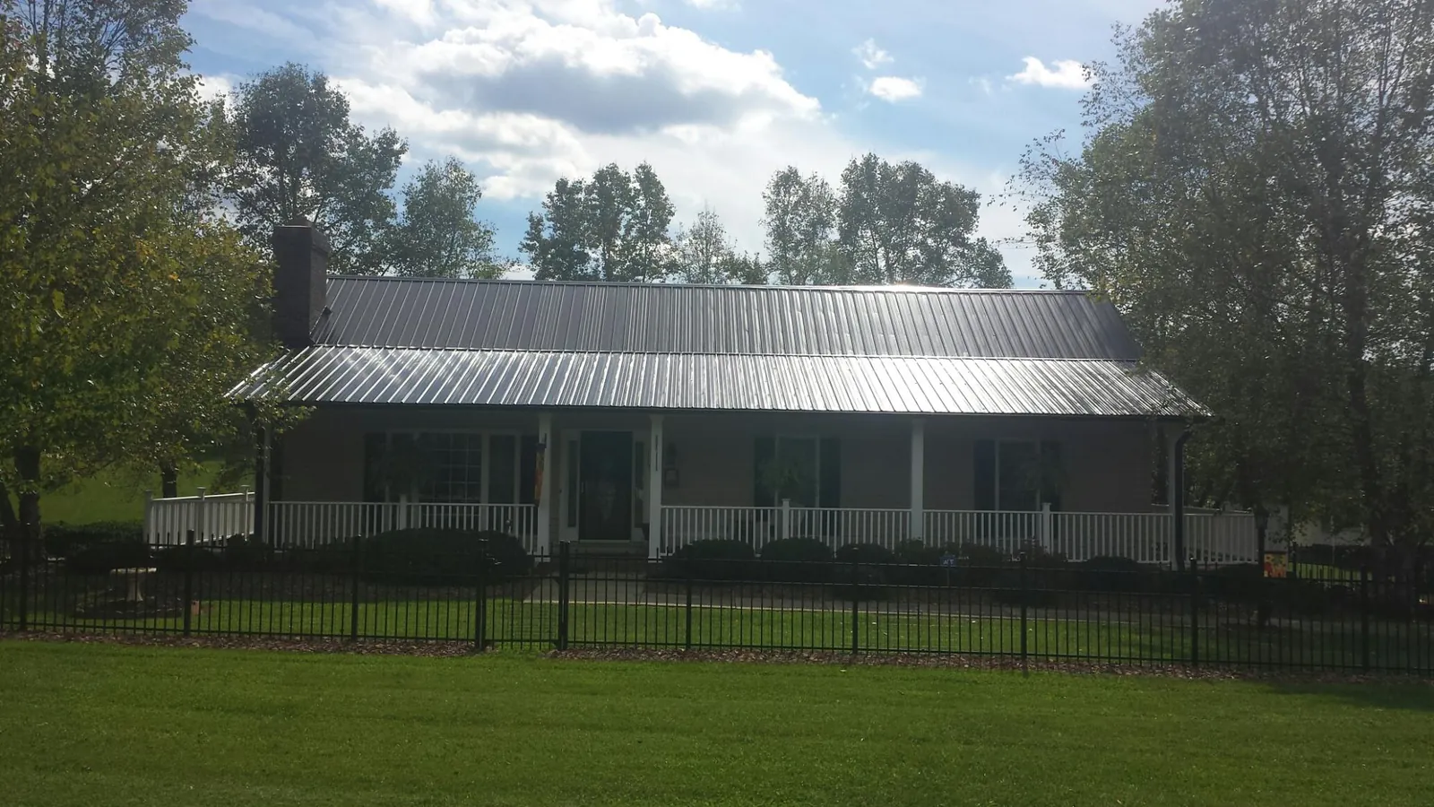 Gray metal roof on a brick ranch with a full width front porch — Gutter Guard Installation work by our crew in Garvin